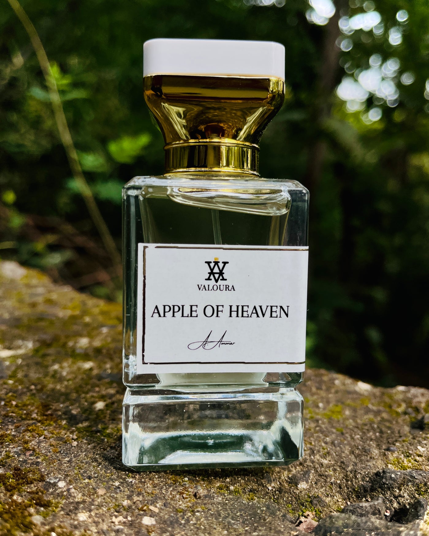 Perfume bottle labeled 'Apple of Heaven' by Valoura on a stone surface with a blurred natural background