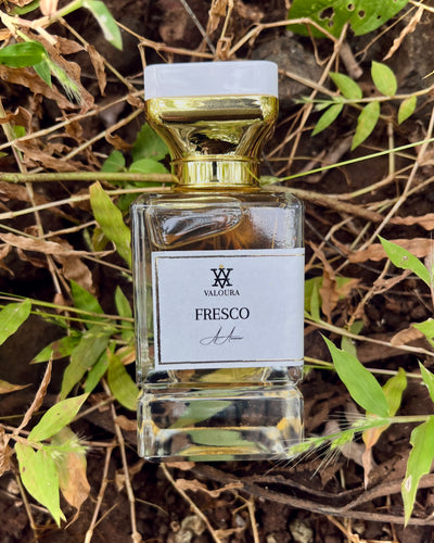 Perfume bottle labeled 'Fresco' by Valoura on a natural background with leaves and twigs .