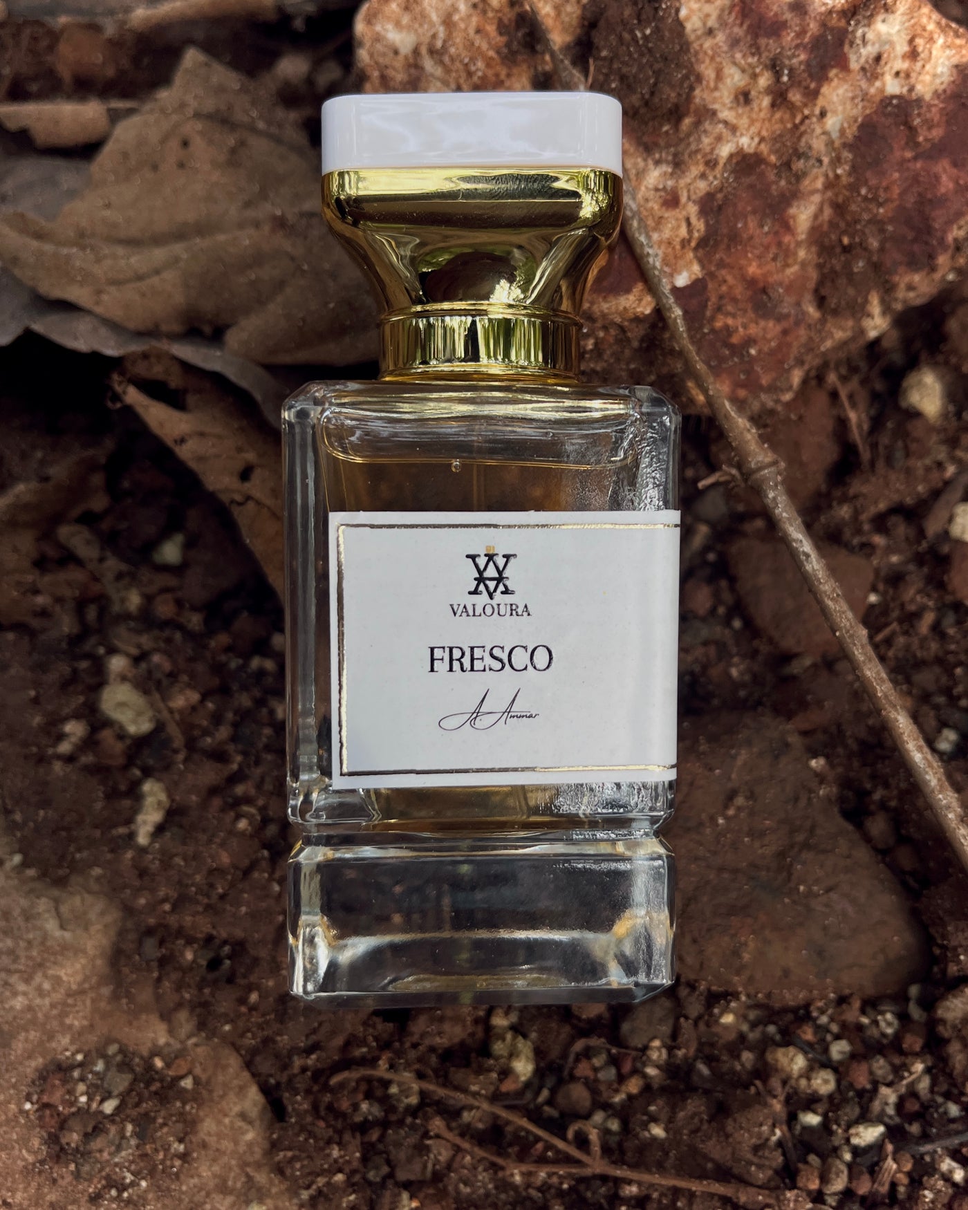 Perfume bottle labeled 'Fresco' by Valoura on a natural stone dirt   background