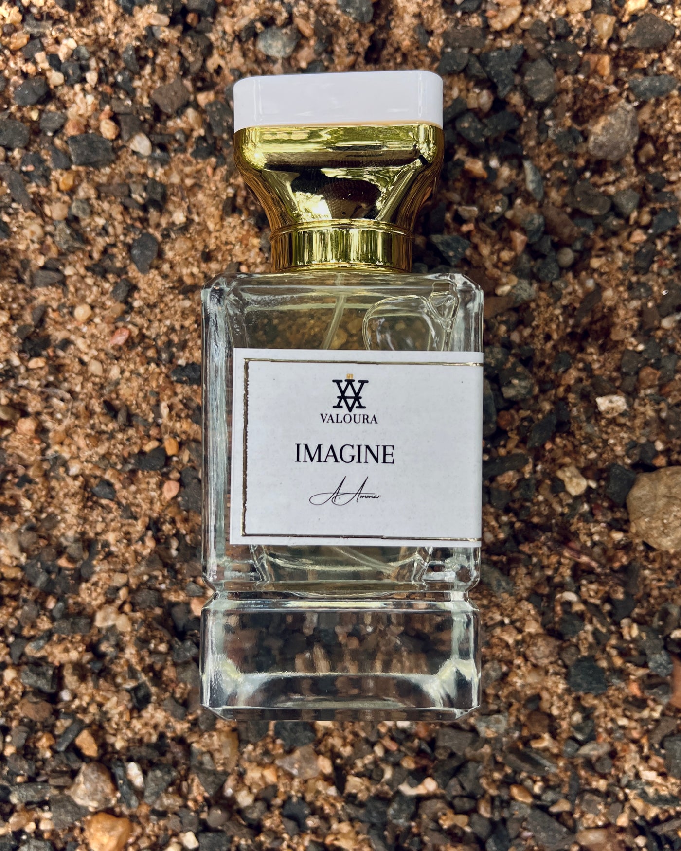 Perfume bottle 'Imagine' by Valoura on a sand textured surface