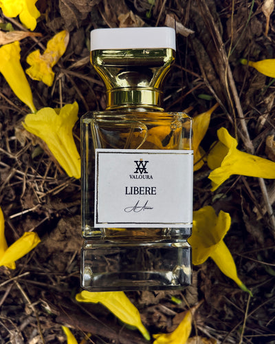 Valoura Libere perfume bottle with gold cap on a natural background with yellow flowers.