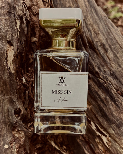 Perfume bottle labeled 'Miss Sin' by Valoura on a wooden background