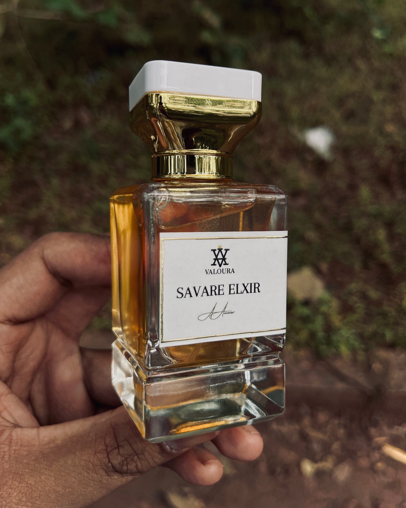 Perfume bottle labeled 'Savare Elixir' by Valoura held by a hand with a blurred natural background