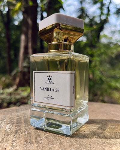 Perfume bottle labeled 'Vanilla 28' with a gold cap on a blurred natural background