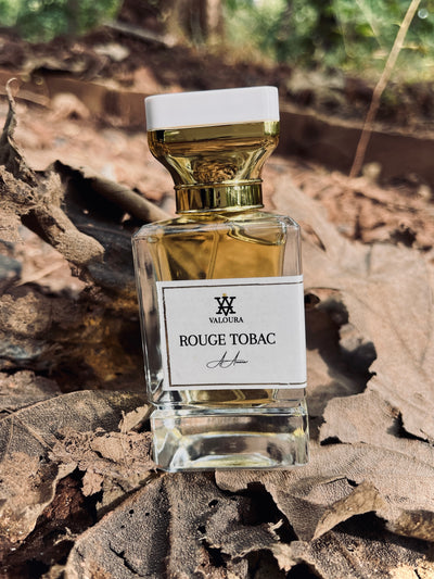 Perfume bottle labeled 'Rouge Tobac' by Valhalla on a dried leaf background